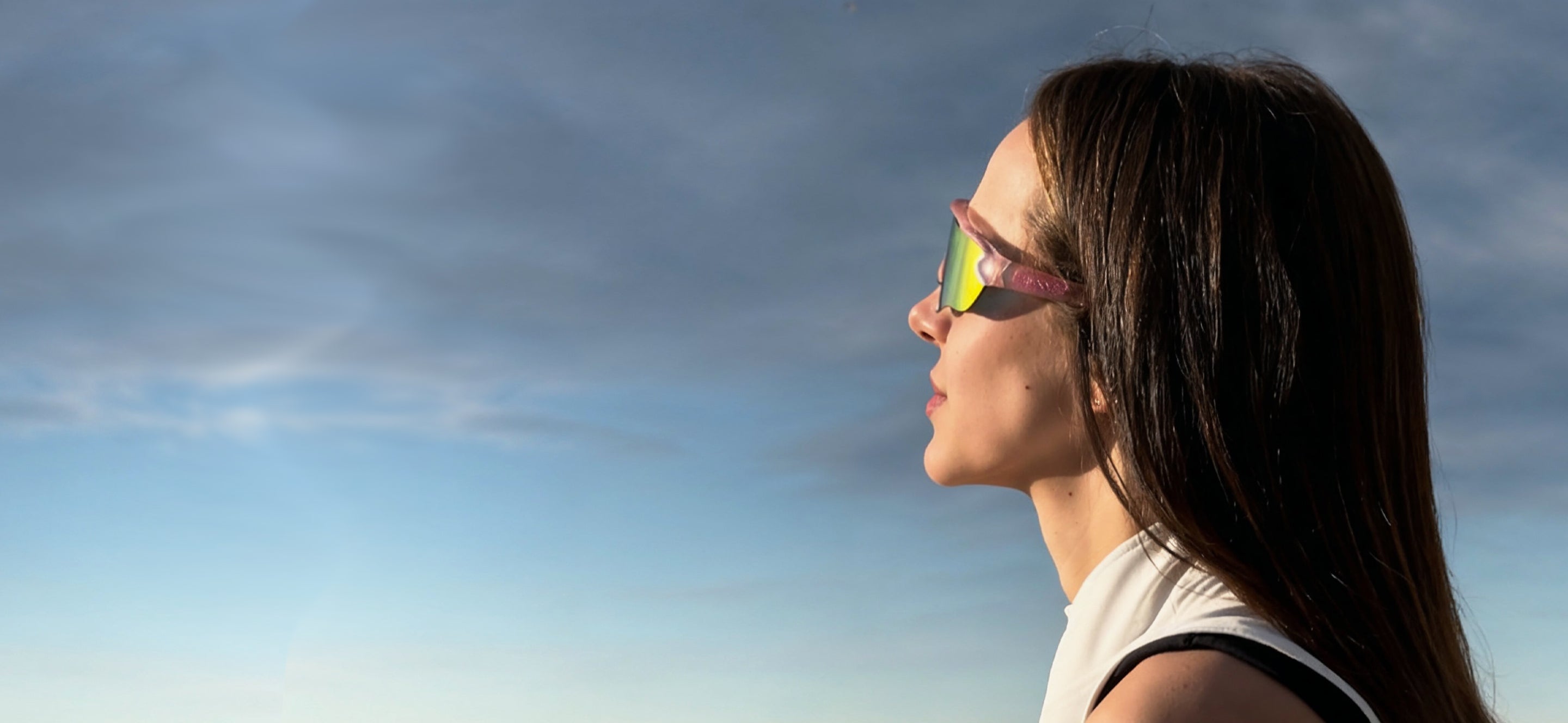 Woman wearing höhen Aero women sports sunglasses with mirrored lenses outdoors at sunset, featuring a sleek athletic design and lightweight fit.