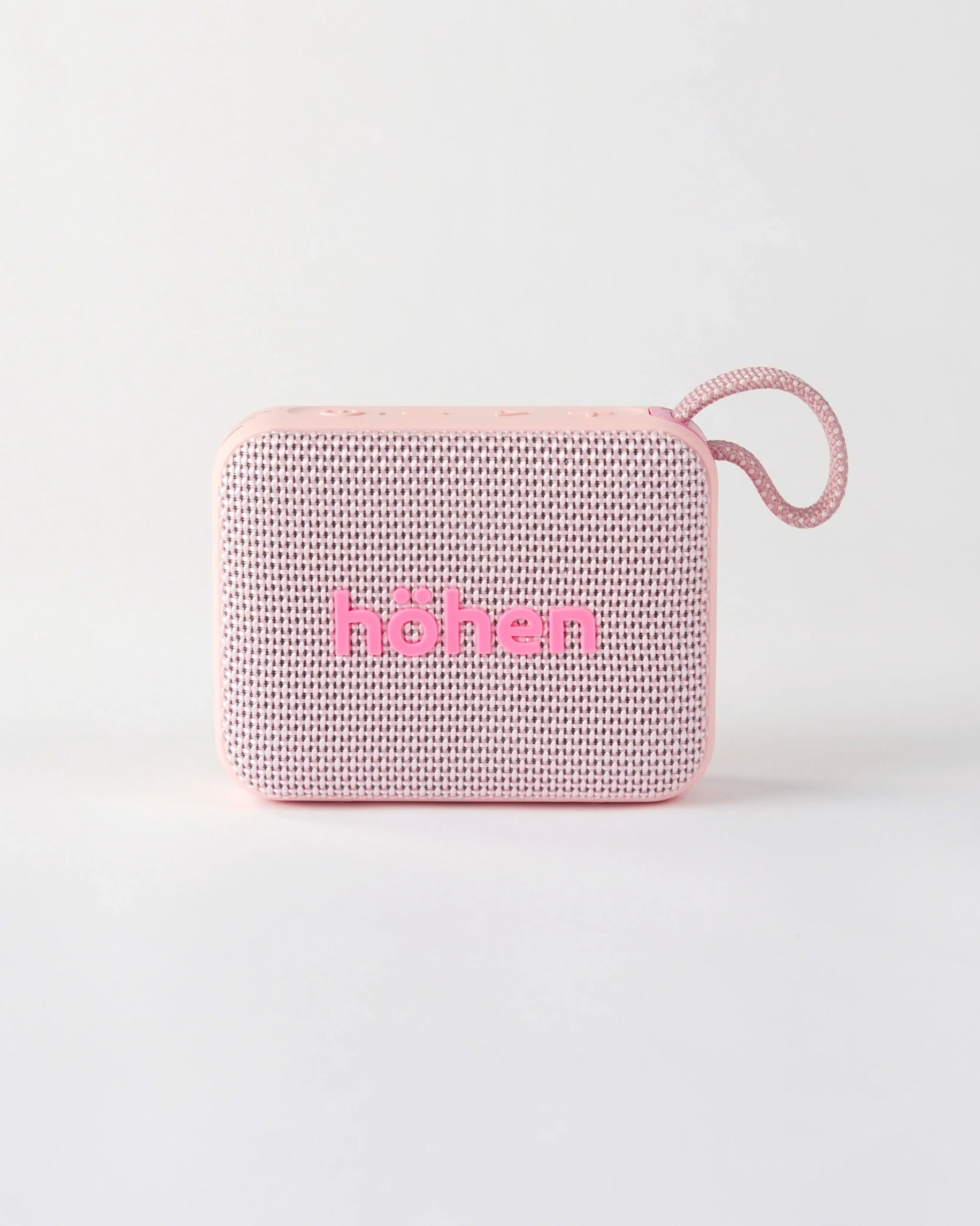 Front view of the compact höhen move portable bluetooth speaker in pale pink with a woven fabric grille and carrying loop