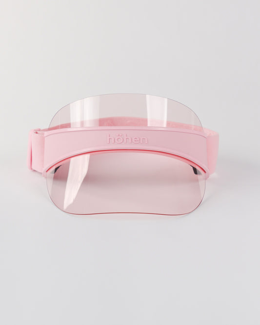 Front view of a pink höhen soleil women’s sports visor with a clear pink transparent shield and adjustable elastic band on a white background.