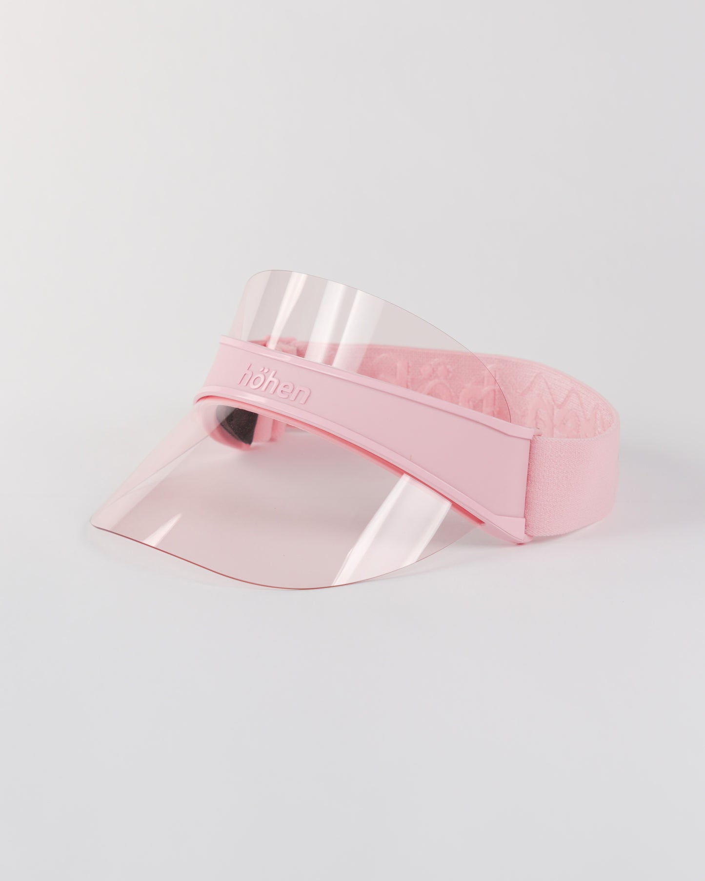 Side view of a pink höhen soleil women’s sports visor with a clear pink transparent shield and adjustable elastic band on a white background.