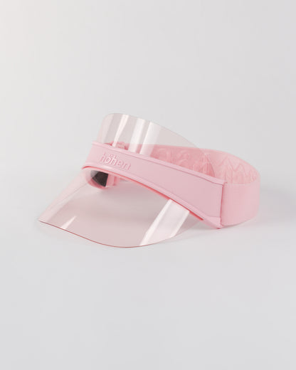 Side view of a pink höhen soleil women’s sports visor with a clear pink transparent shield and adjustable elastic band on a white background.